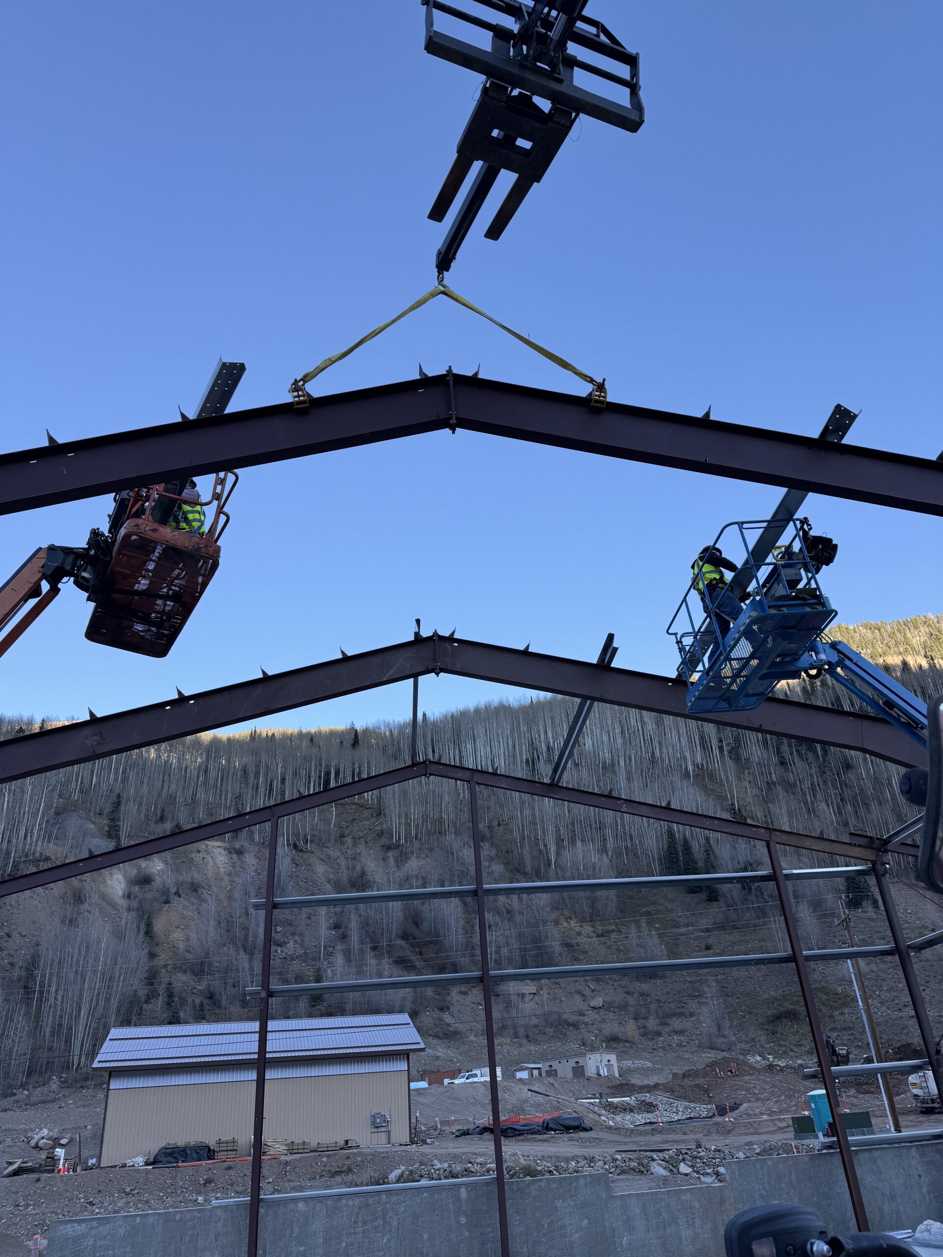 Crews setting the ridge beam from two boom lifts